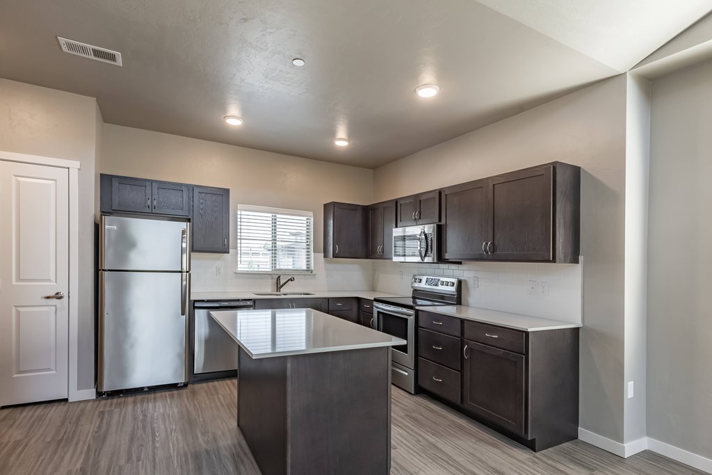 A kitchen with dark wood cabinets and stainless steel appliances. at Harper Ridge Apartments, Idaho, 83642