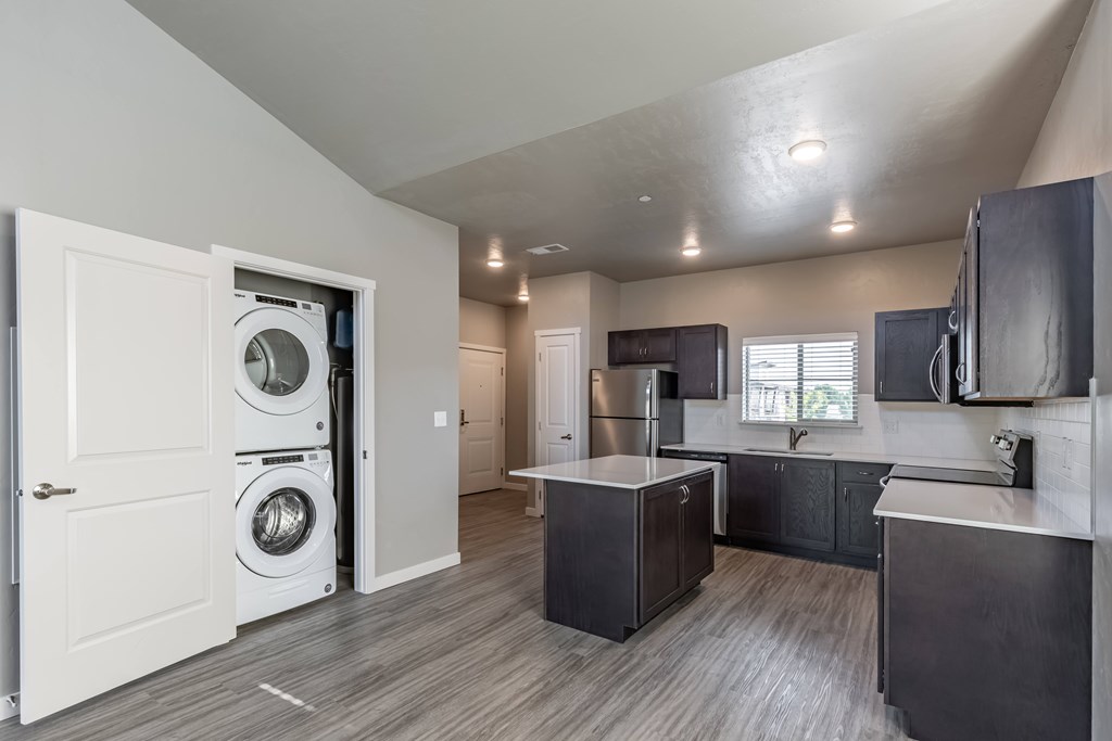 A modern laundry room with a washer and dryer built into the cabinetry. at Harper Ridge Apartments, Idaho