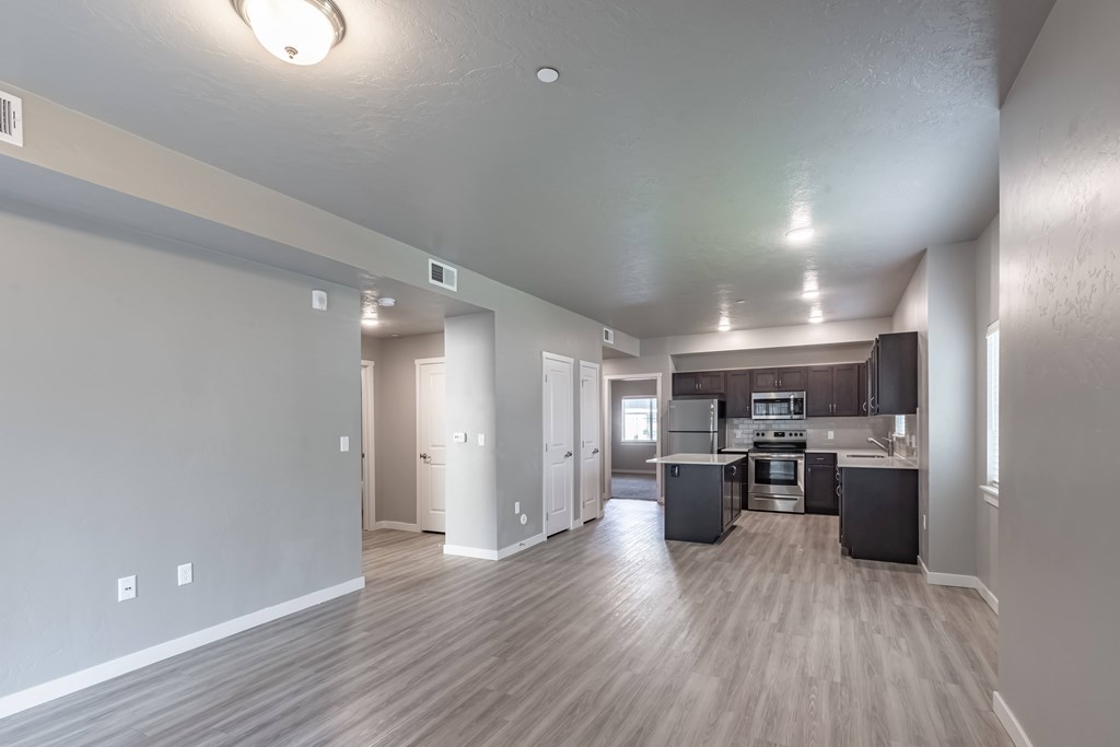 A spacious kitchen and living room with wood flooring and white walls. at Harper Ridge Apartments, Meridian