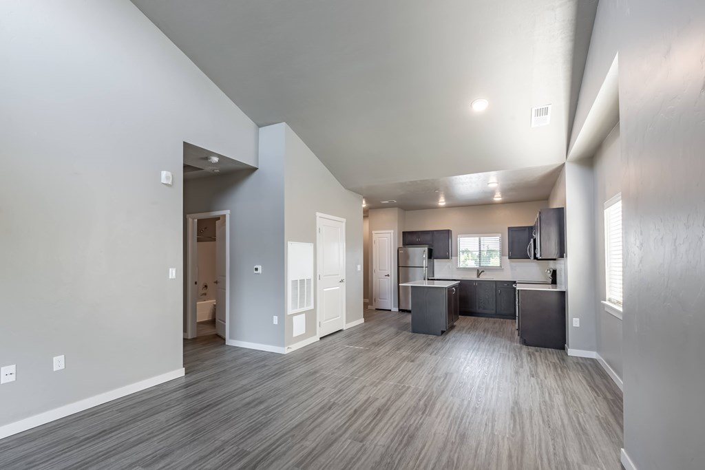 A spacious living area with a kitchen in the background. at Harper Ridge Apartments, Meridian, ID