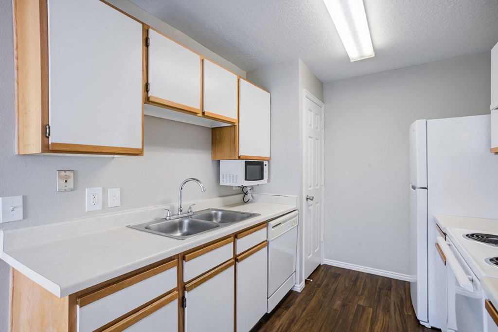 an empty kitchen with white appliances and wooden cabinets