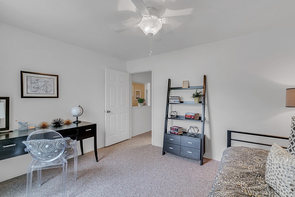 a bedroom with a desk and a couch and a ceiling fan