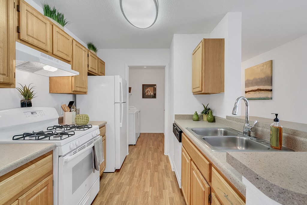 a kitchen with wooden cabinets and white appliances and a sink