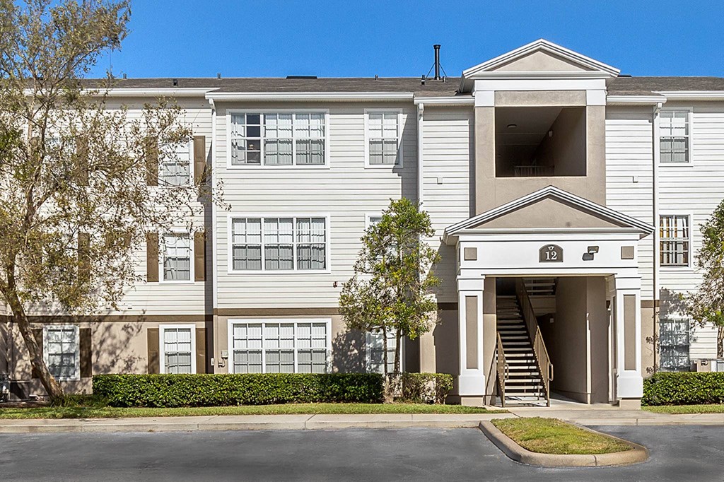 a white apartment building with stairs and a driveway