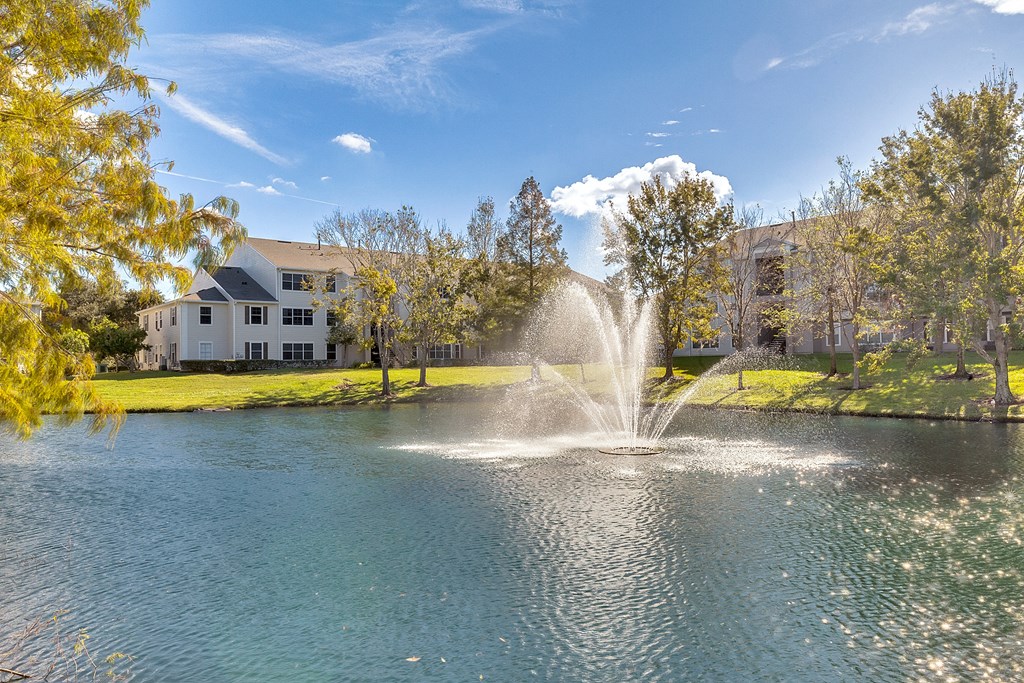 a fountain in a pond with a building in the background