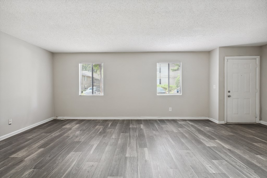 the living room of an empty house with wood floors and a door