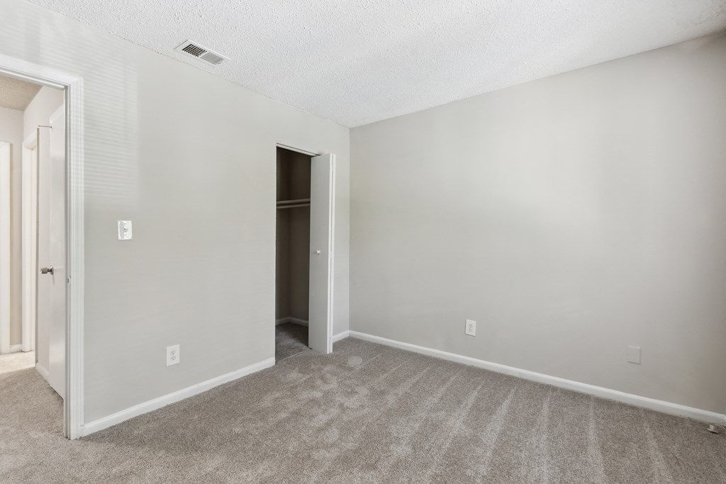 an empty living room with carpet and a door to a closet
