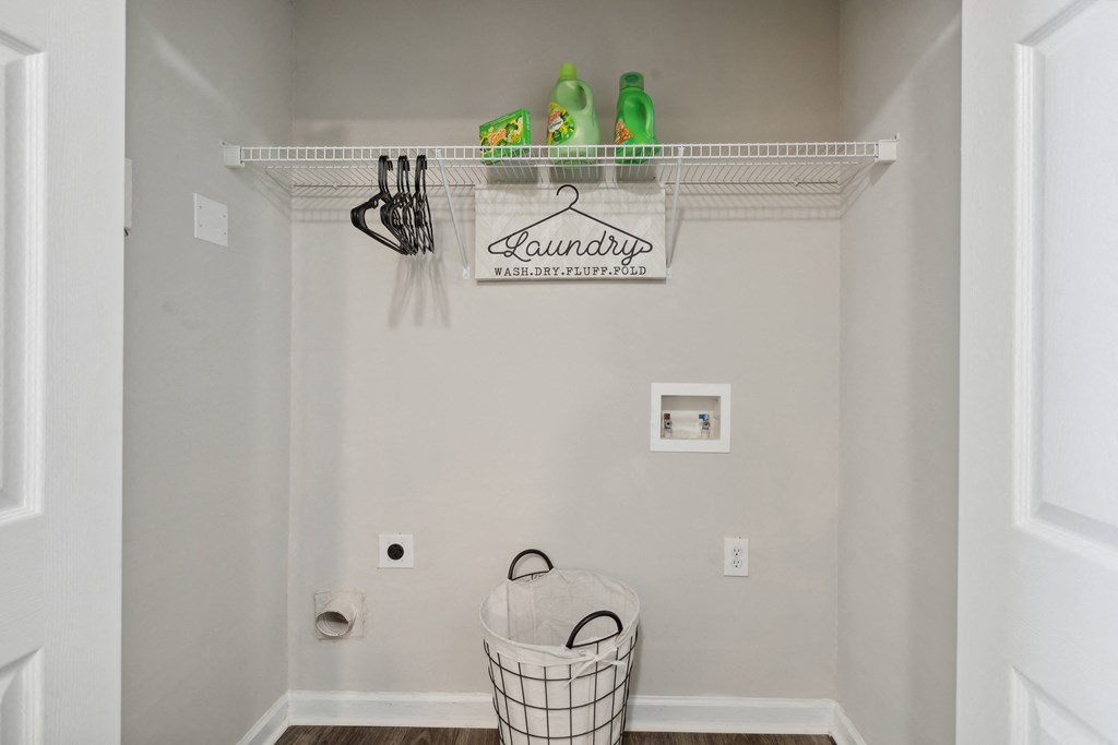 a laundry room with a basket and a sign on the wall and a rack above