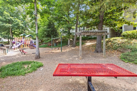 a park with a red picnic table and playground equipment
