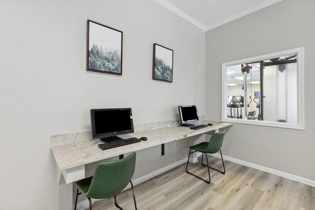 two computers on a desk in a room with a window