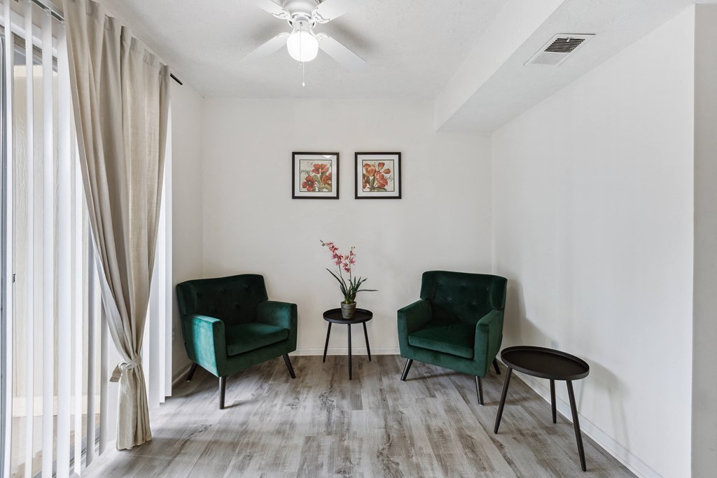 a living room with two green chairs and a ceiling fan