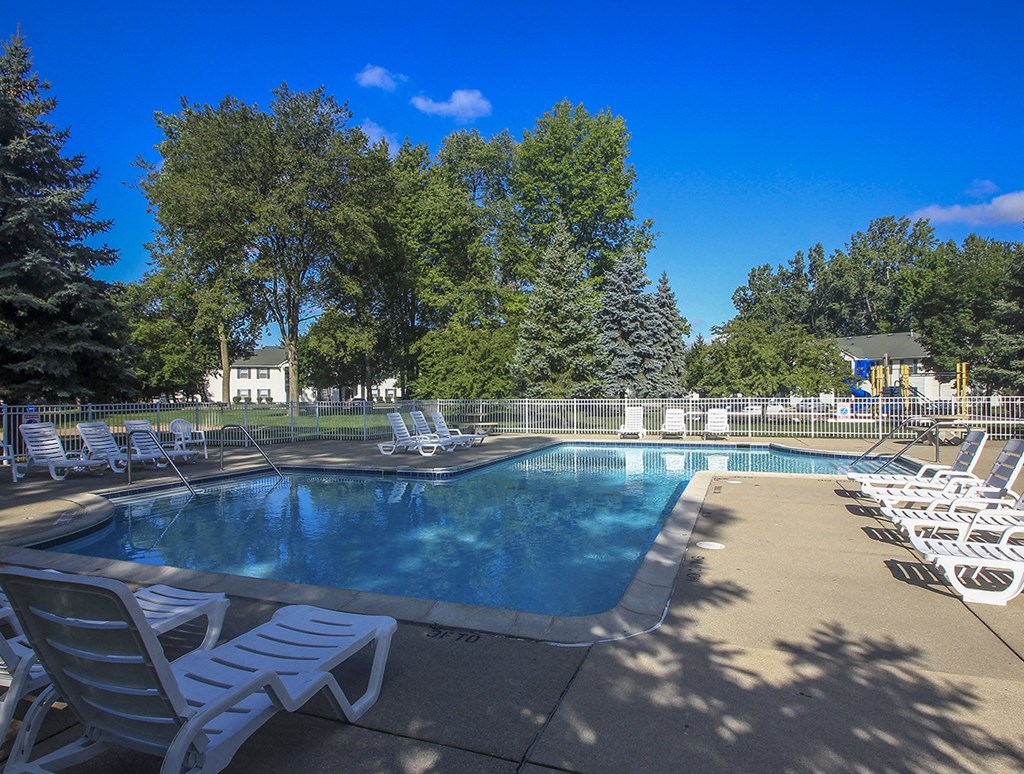 a resort style pool with chairs around it and trees