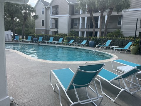 an image of a resort style pool with lounge chairs and umbrellas