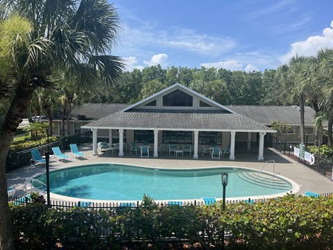 a resort style pool with lounge chairs and a pavilion in the background