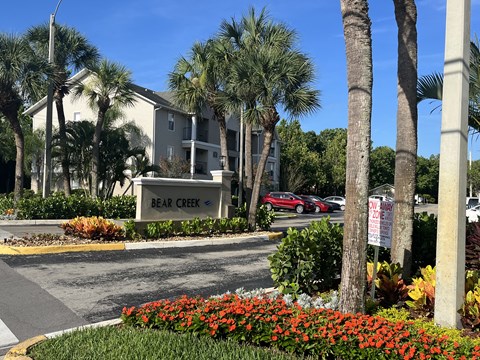 a sign that says bear creek in front of a building with palm trees