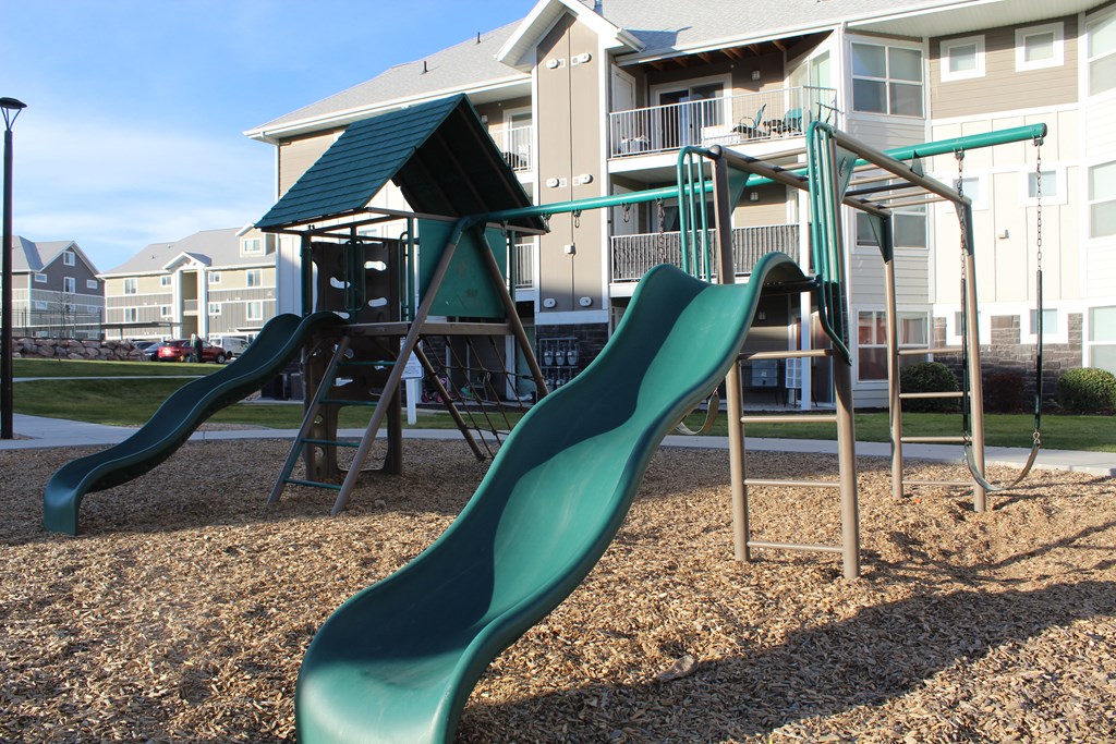 a playground with slides and swings in front of a building