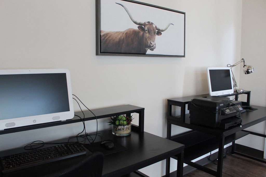 a desk with a computer and a picture of a bull on the wall