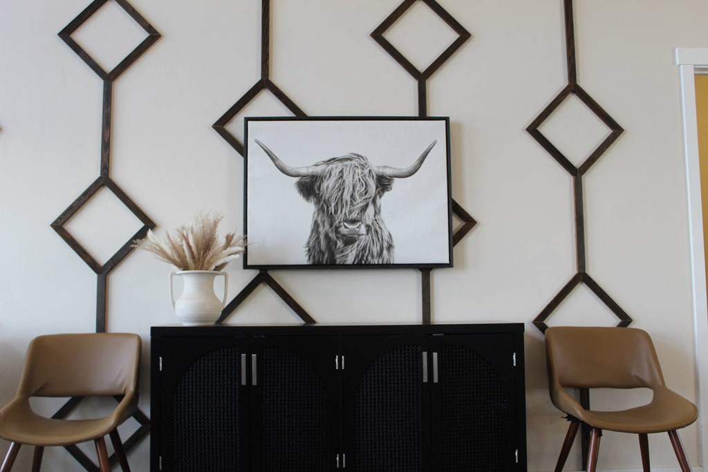 a living room with a black cabinet and a bull print on the wall
