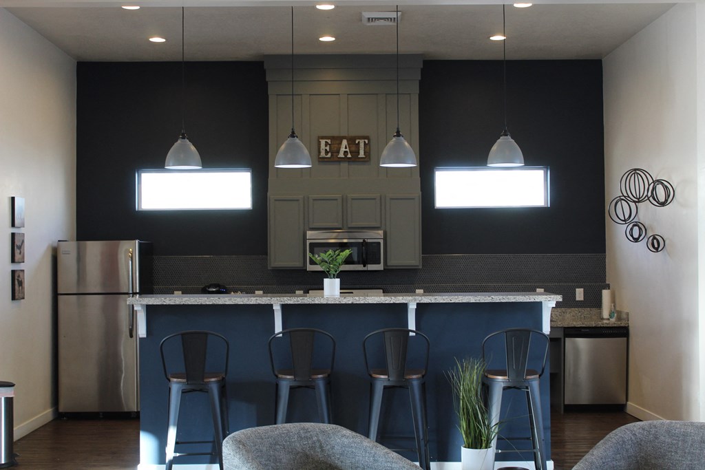 a kitchen with a bar with blue stools in front of it