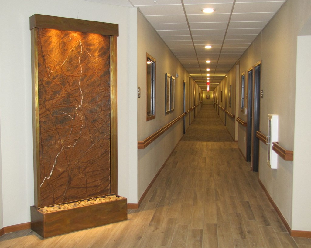 a long hallway with wood floors and a marble wall in a hospital