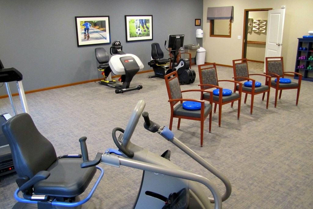 a gym with exercise equipment and chairs in a therapy room