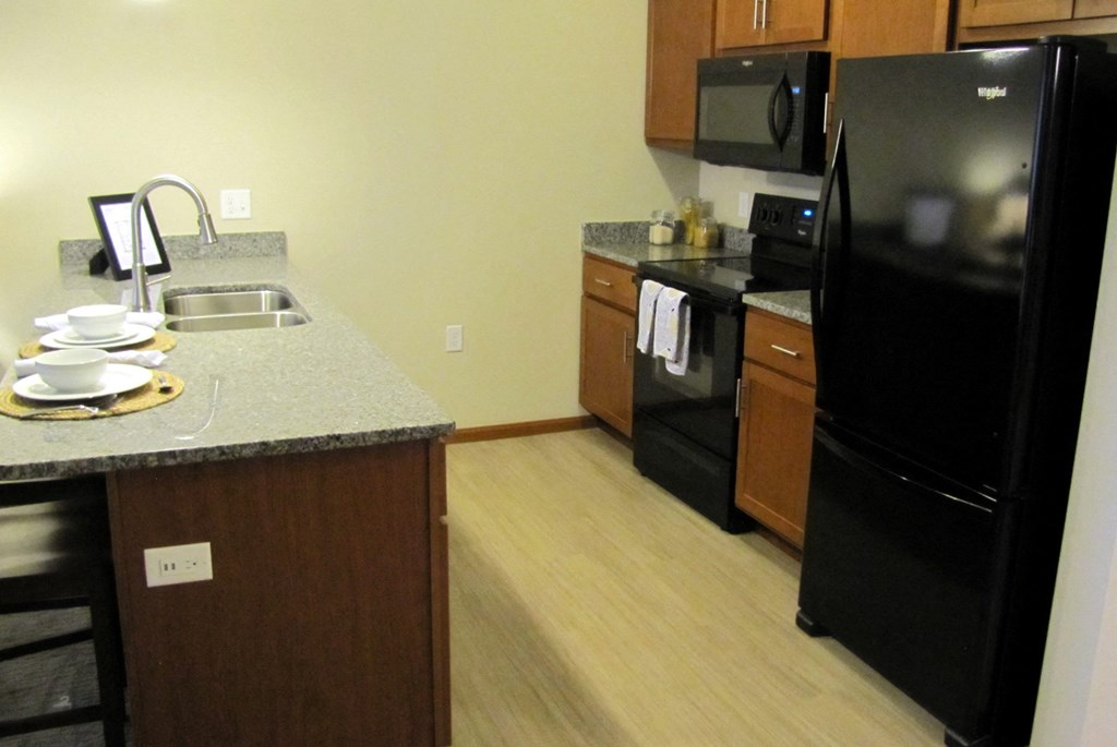 a kitchen with black appliances and a granite counter top