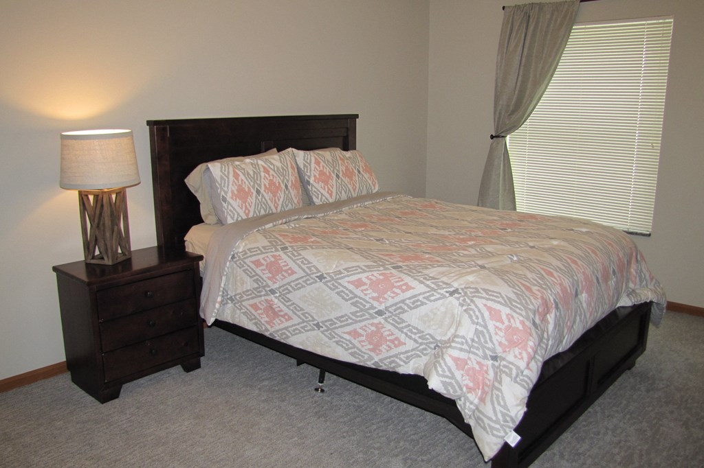 a bedroom with a bed and a nightstand and a window