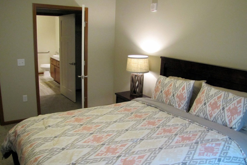 a bedroom with a large bed and a door to a bathroom