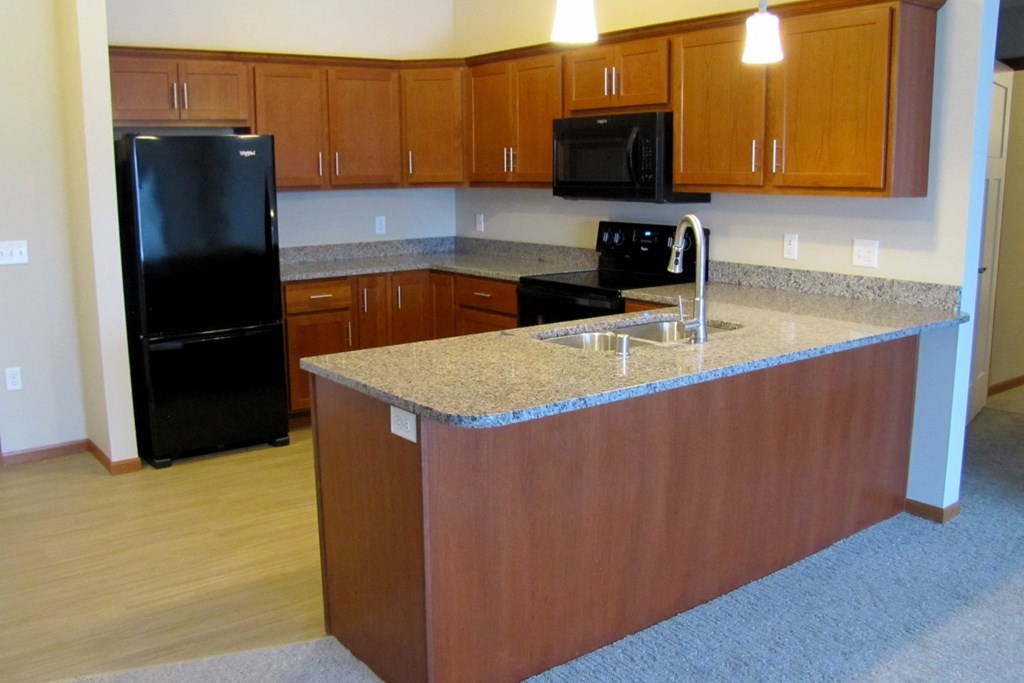 an empty kitchen with granite counter top and black appliances