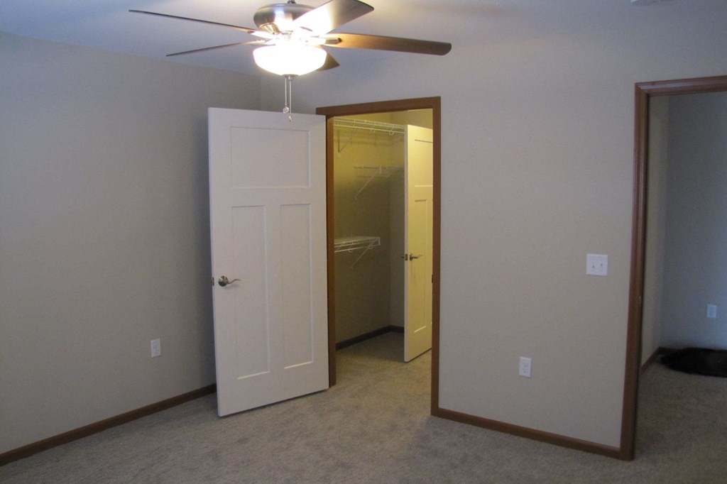 a room with a ceiling fan and a closet and a door to a bathroom