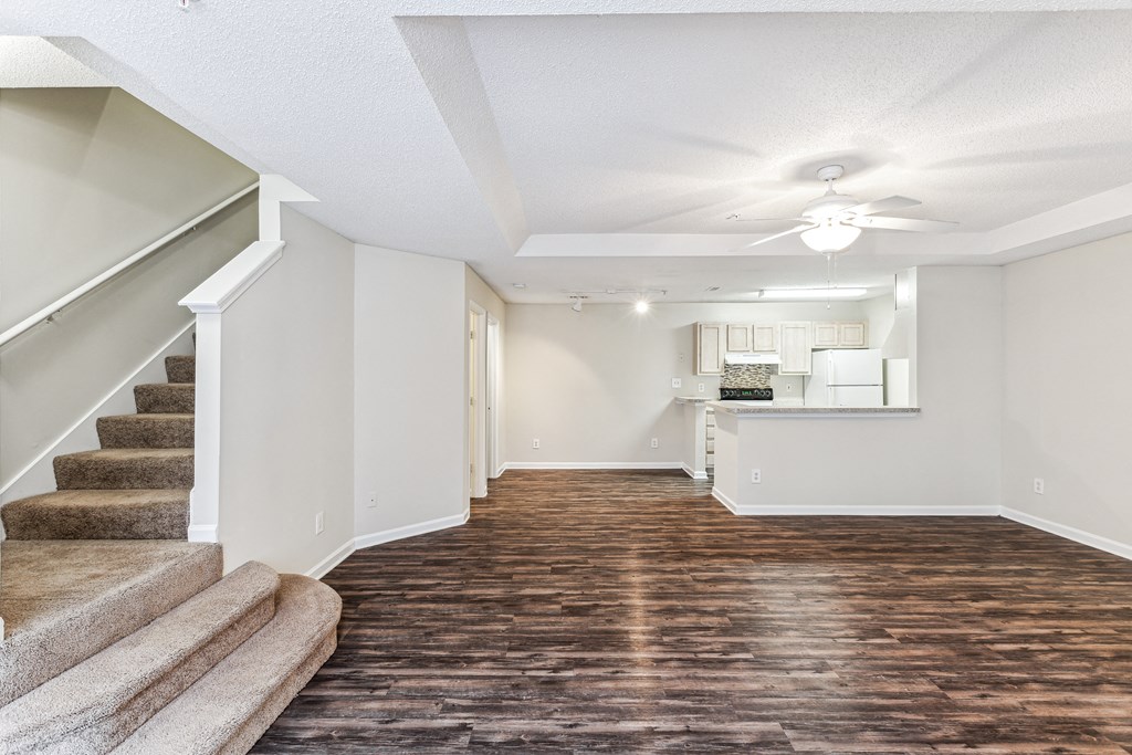 an empty living room with stairs and a kitchen