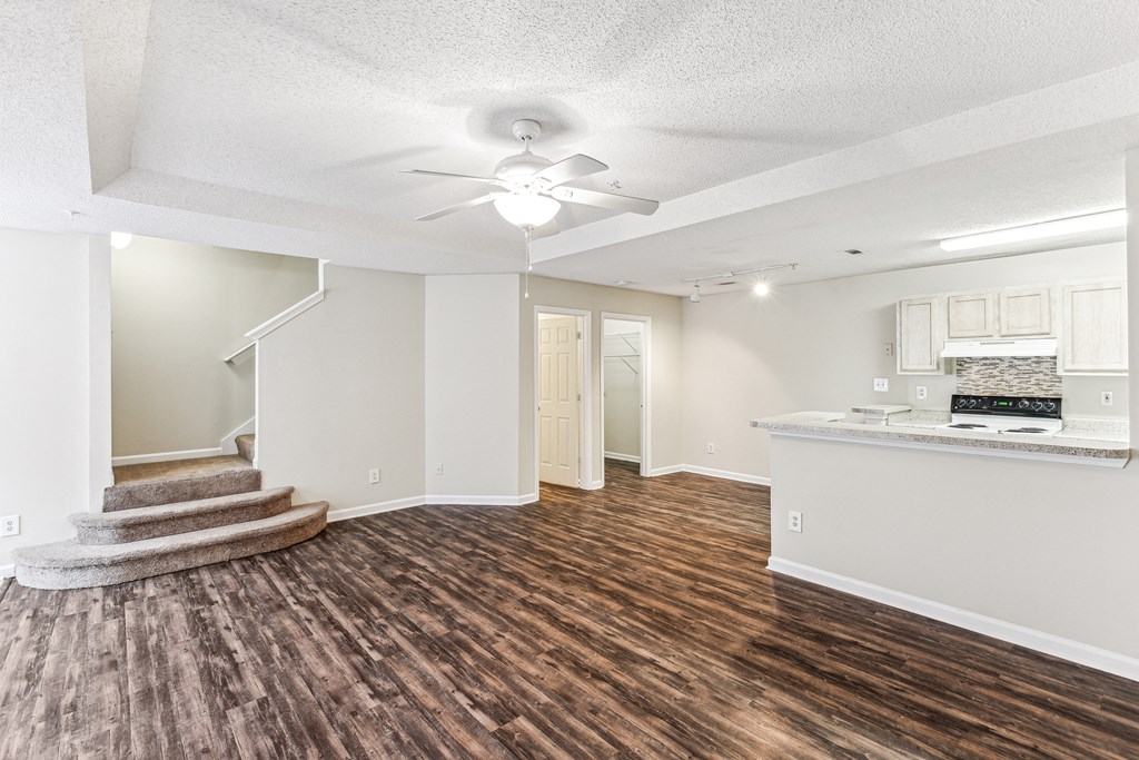 a renovated living room with a kitchen and a ceiling fan