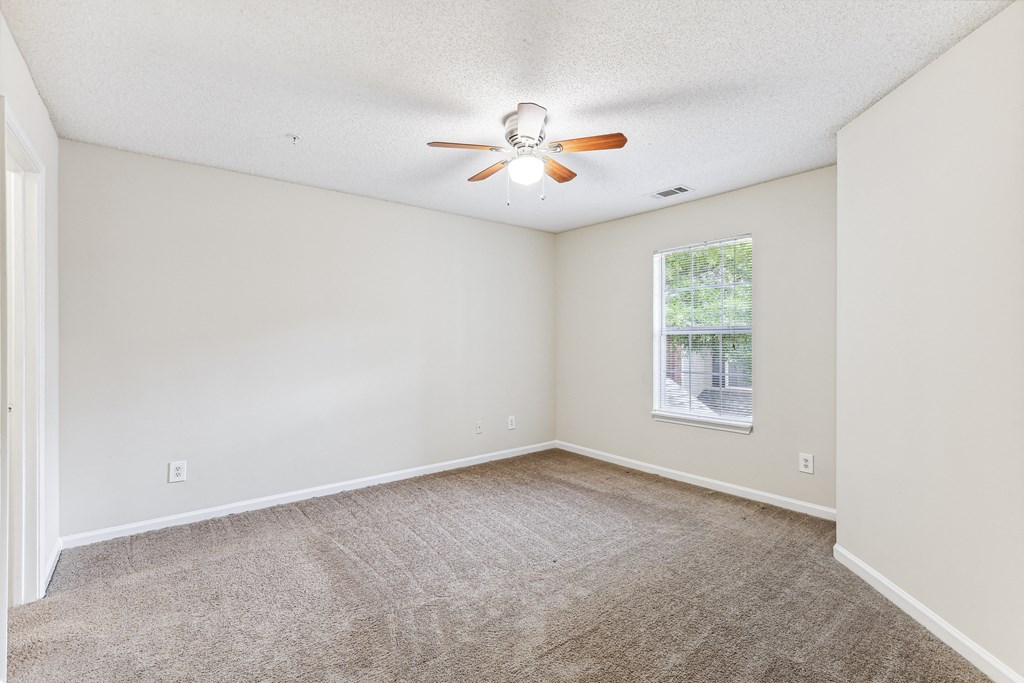 an empty living room with a ceiling fan and a window