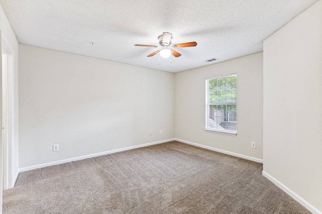 an empty living room with a ceiling fan and a window