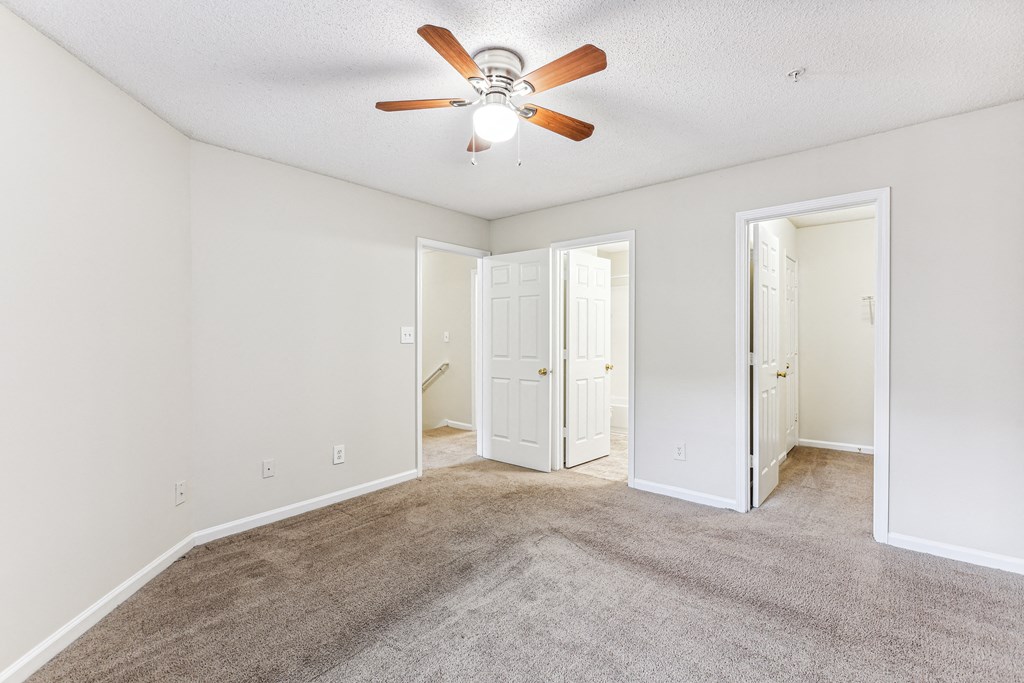 a spacious living room with carpet and a ceiling fan
