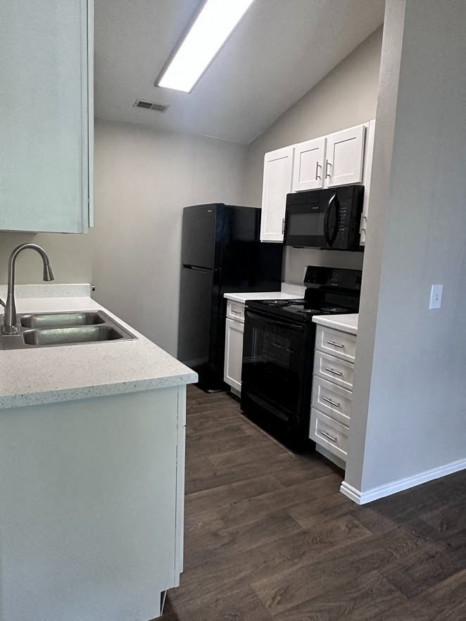 a kitchen with a sink and a black refrigerator