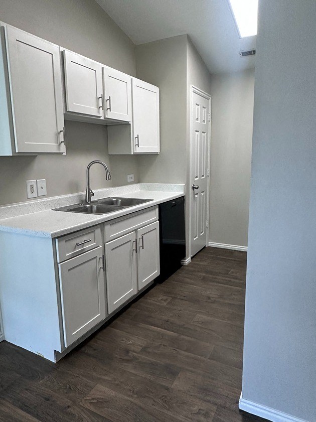an empty kitchen with white cabinets and a sink