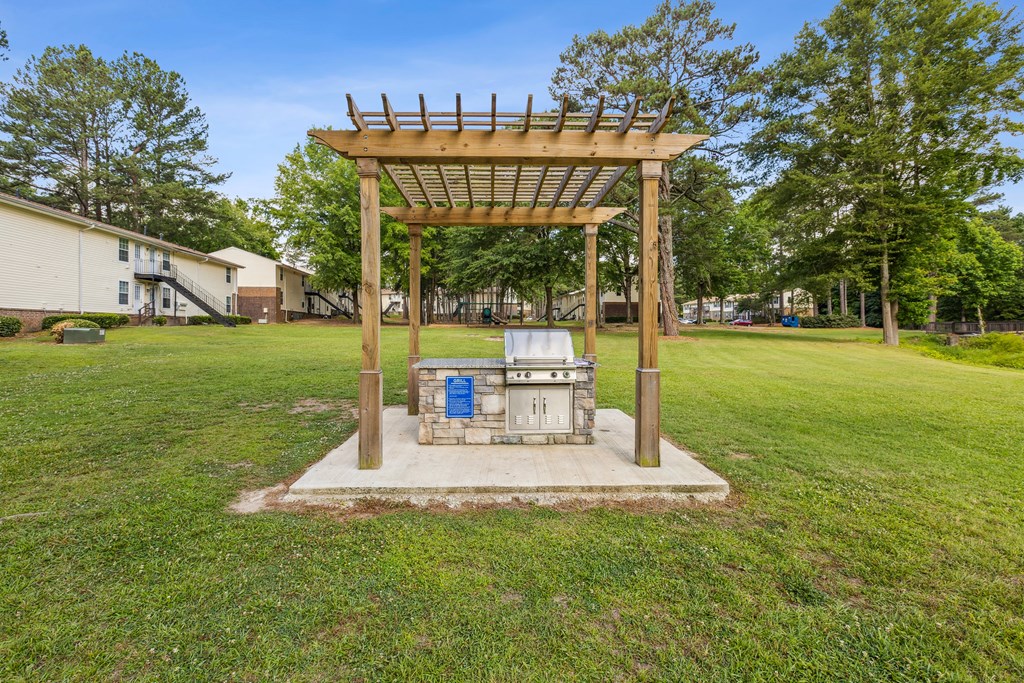 A wooden structure with a roof and a blue door is in the middle of a grassy area.