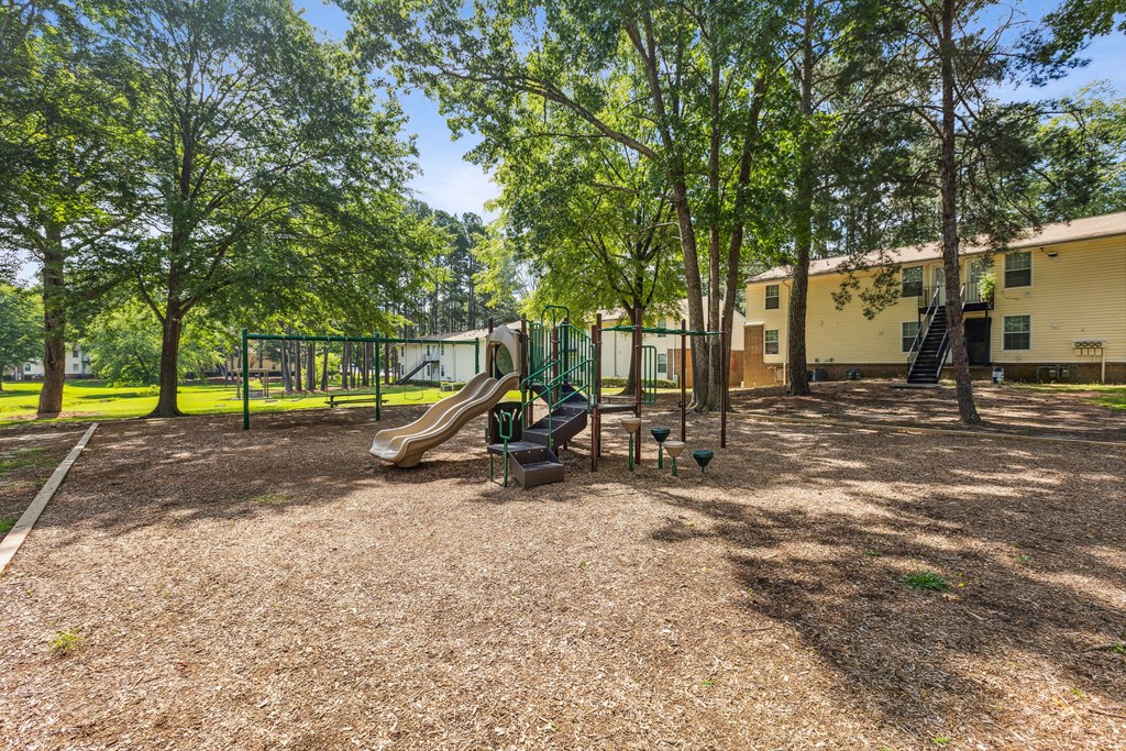 A playground with a slide and a green fence.