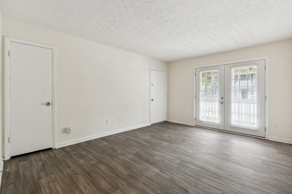 the living room of an apartment with white walls and wood floors