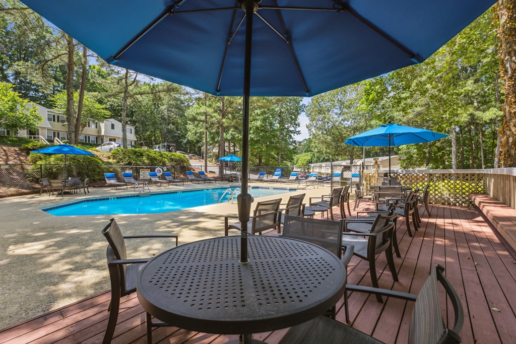 a patio with tables and umbrellas and a swimming pool