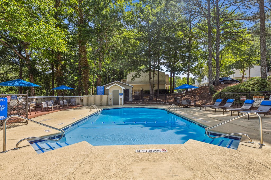 our resort style swimming pool is surrounded by chairs and trees