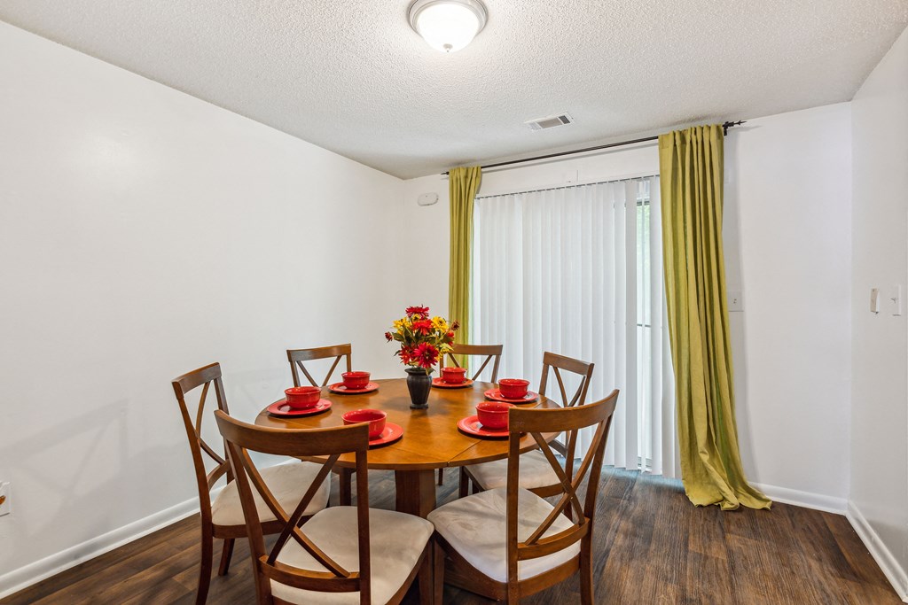 a dining room with a table and chairs and a window with yellow curtains