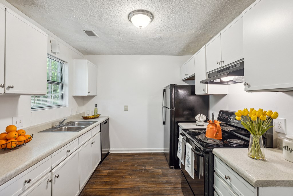 a kitchen with white cabinets and a black refrigerator