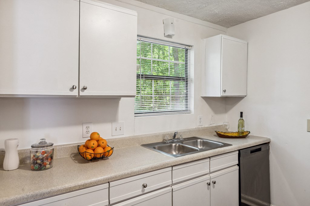 a kitchen with white cabinets and a sink and a window