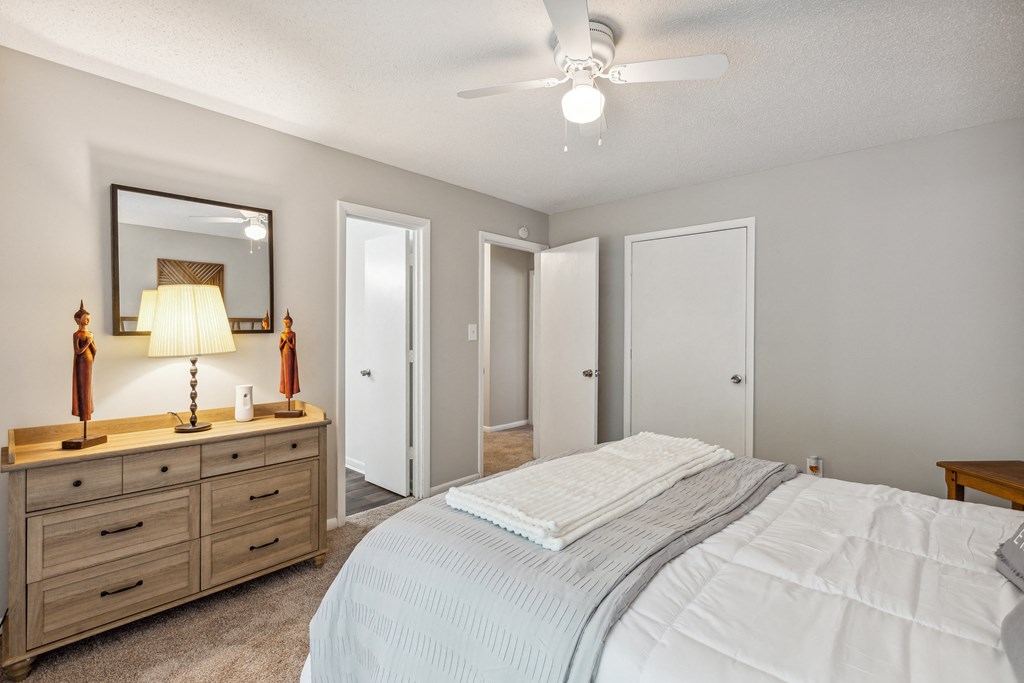 a bedroom with a bed and a dresser and a ceiling fan