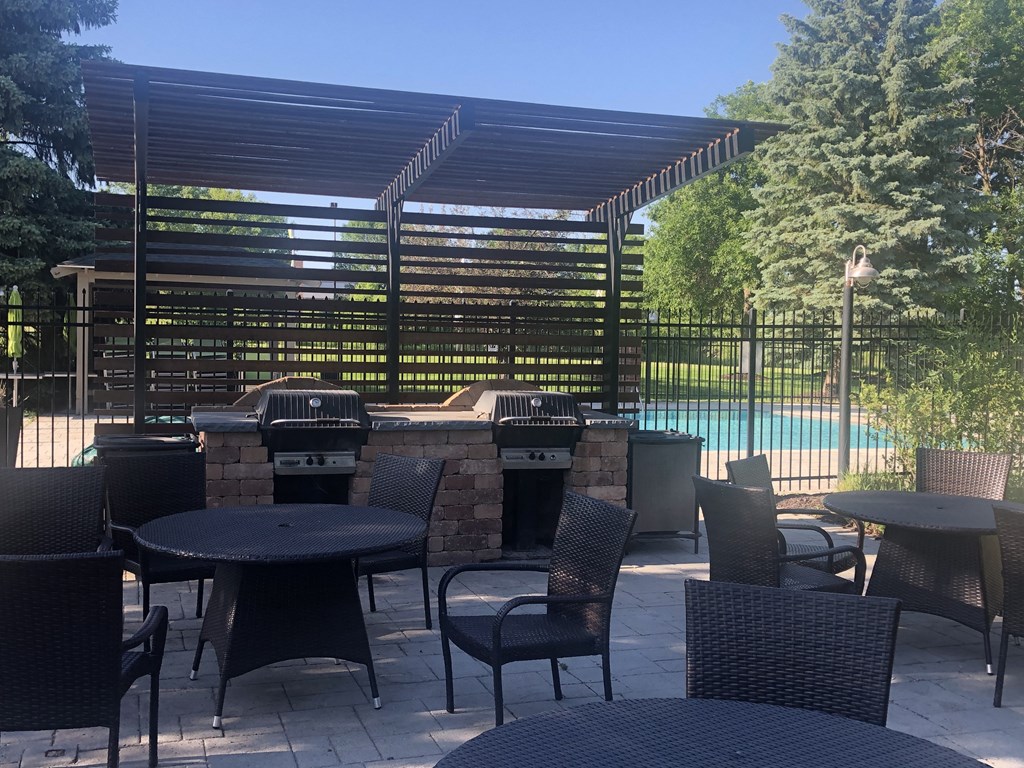 a patio with tables and chairs and a barbecue grill