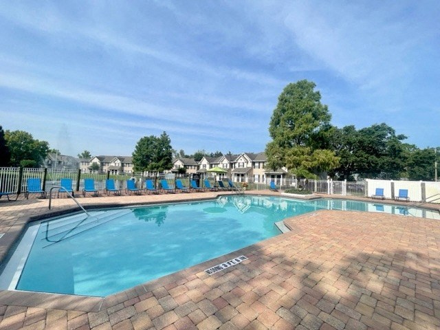 a resort style pool with blue chaise lounge chairs and trees in the background