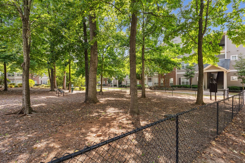a fenced in dog park with trees and houses