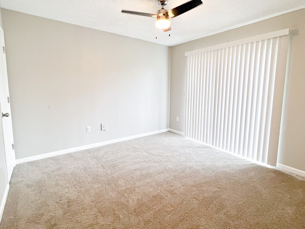 an empty bedroom with a ceiling fan and blinds